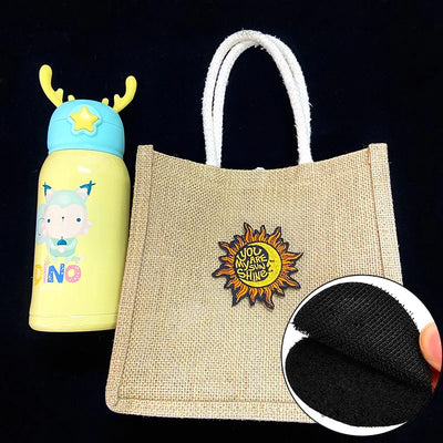 Jute bag with sun design patch and cartoon water bottle on black background