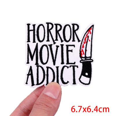 Patch with 'Horror Movie Addict' text and a knife graphic held by a hand, on a white background.