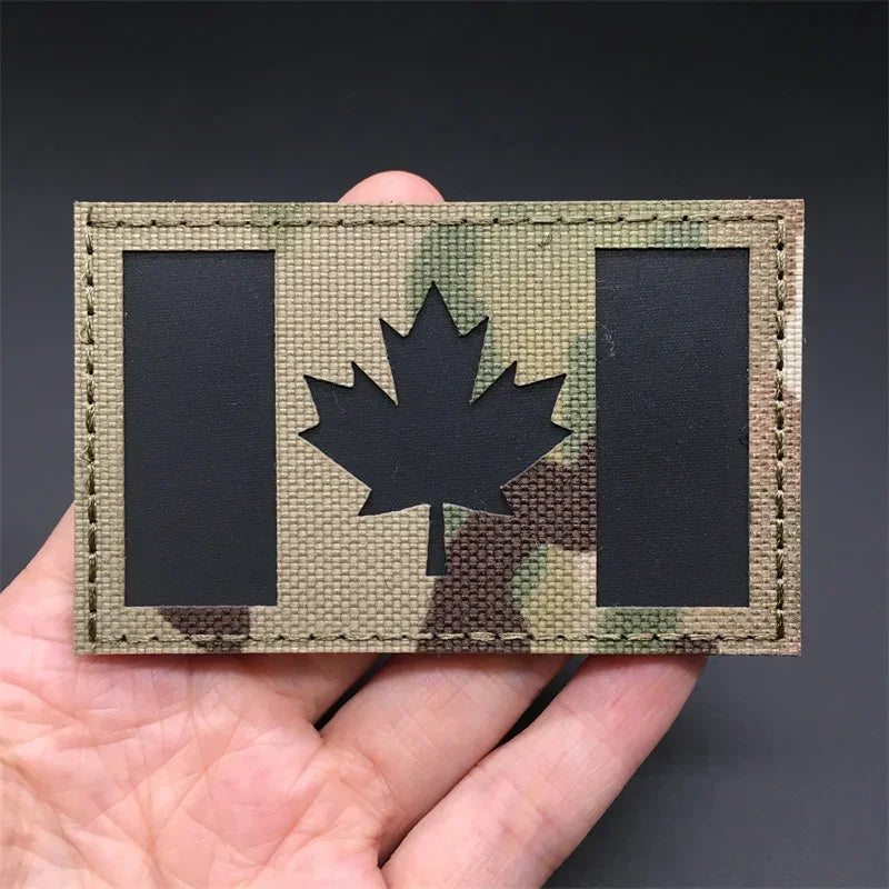 Canada flag Camouflage patch held in a hand against a dark background