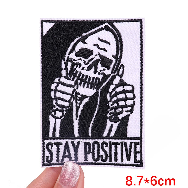 Skeleton holding a microphone with 'Stay Positive' text, held by a hand.