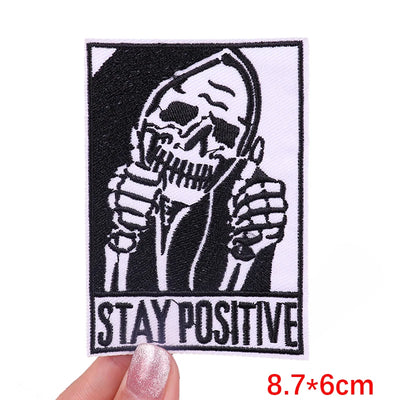 Skeleton holding a microphone with 'Stay Positive' text, held by a hand.