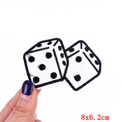 Two dice-shaped patches held by a hand with a white background