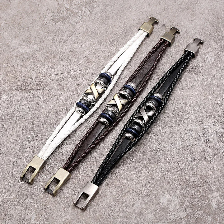 Three braided leather bracelets with metal clasps on a textured surface