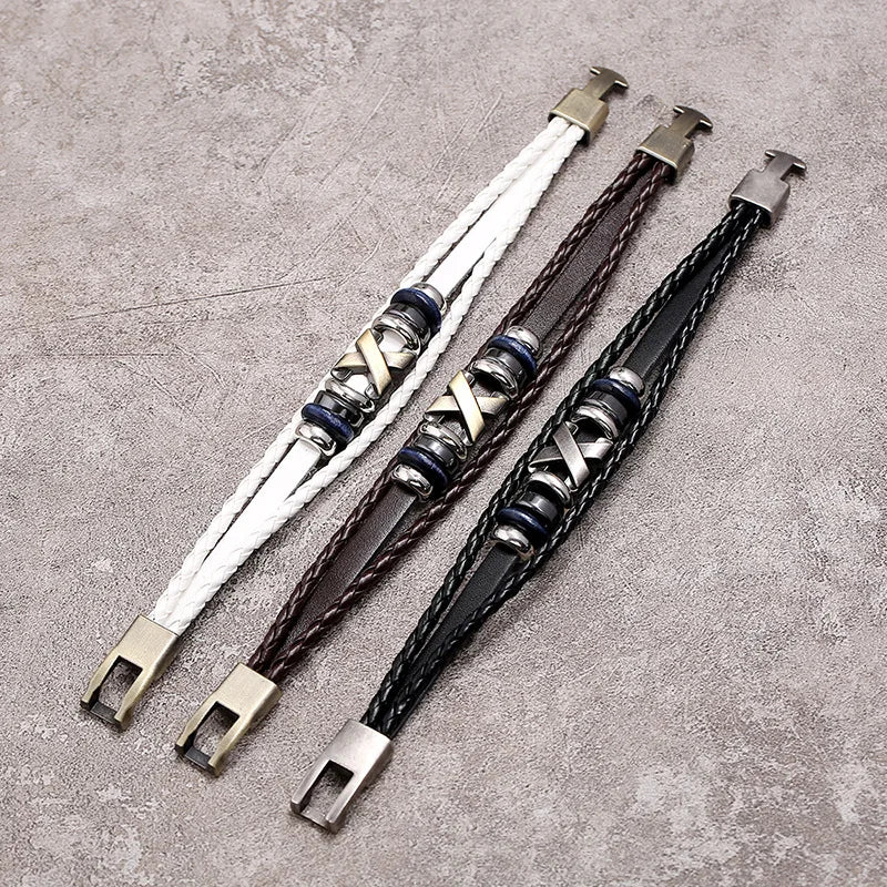 Three braided leather bracelets with metal clasps on a textured surface