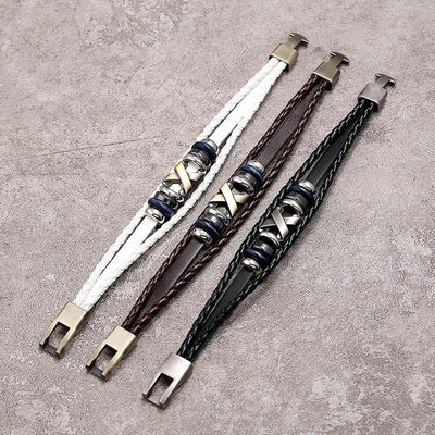 Three braided leather bracelets with metal clasps on a textured surface