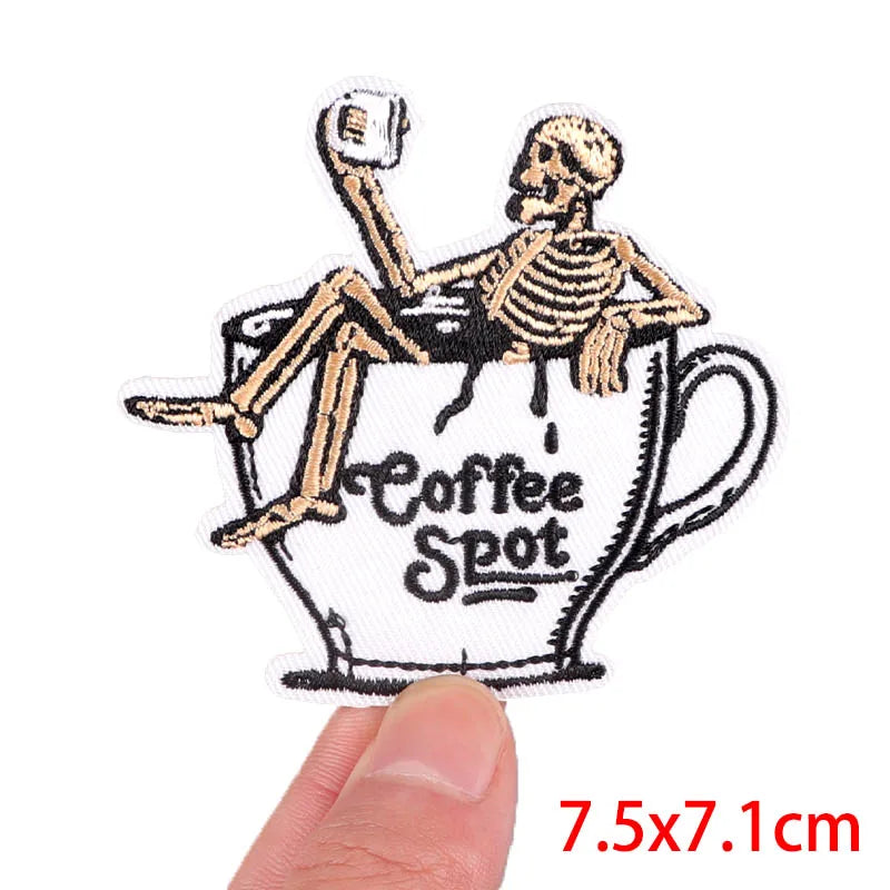 Skeleton sitting in a coffee cup with 'Coffee Spot' text, held by a hand.