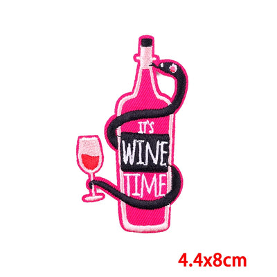 Embroidered patch of a pink wine bottle with a snake, It's Wine Time', and a glass of wine on a white background.