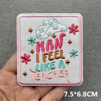 Embroidered patch with text 'Man I feel like a teacher' held by a hand on a gray background