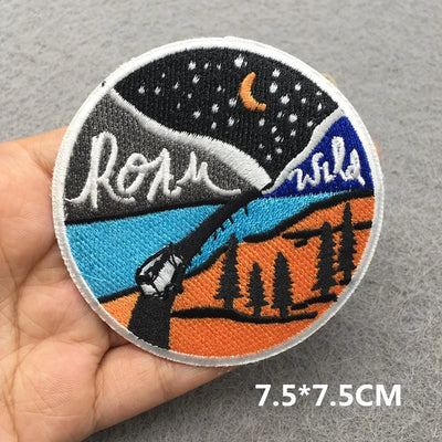 Embroidered patch with nature design held by a hand on a gray background