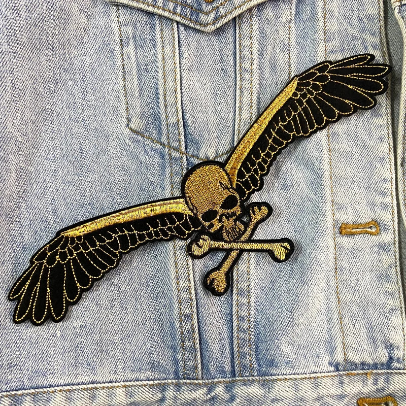 Denim jacket with a skull and crossbones patch featuring wings.