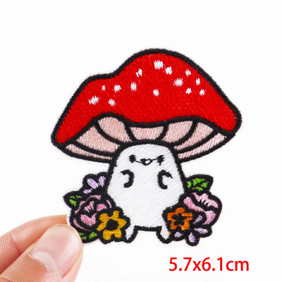 Embroidered patch of a ghost under a red mushroom with flowers on a white background