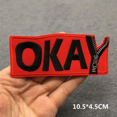 Red patch with 'OKAY' text held in a hand against a gray background