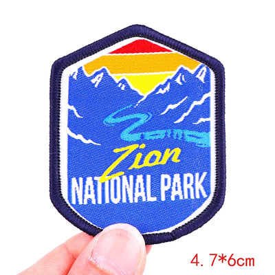 Zion National Park patch held by a hand with mountain design and blue border.