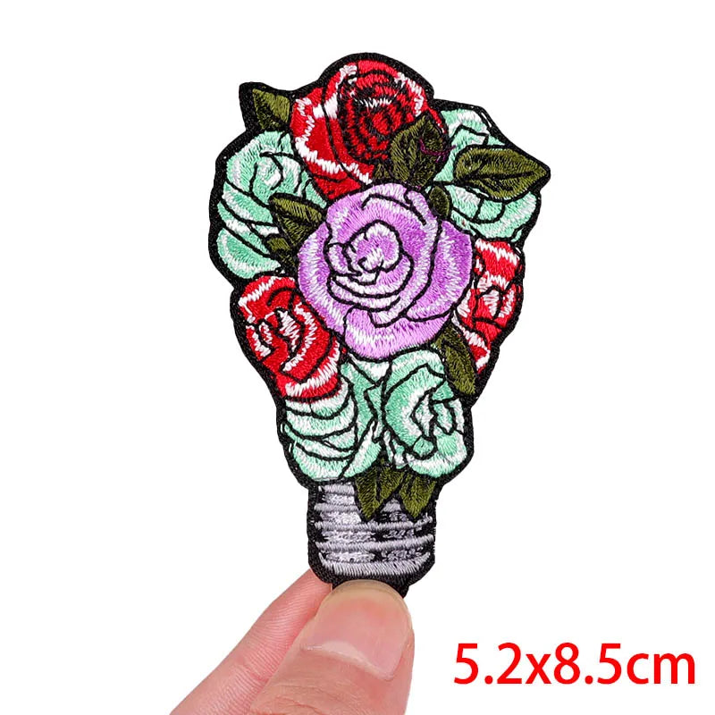 Floral patch held by a finger with dimensions 5.2x8.5cm on a white background