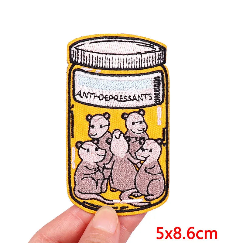 Patch of a jar labeled 'Antidepressants' with cartoon bears on a yellow background, held by a hand.