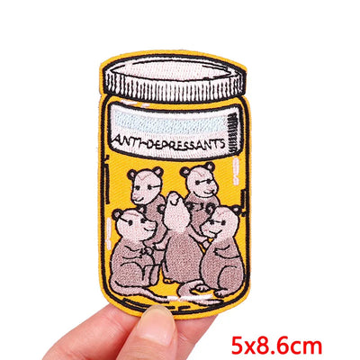 Patch of a jar labeled 'Antidepressants' with cartoon bears on a yellow background, held by a hand.
