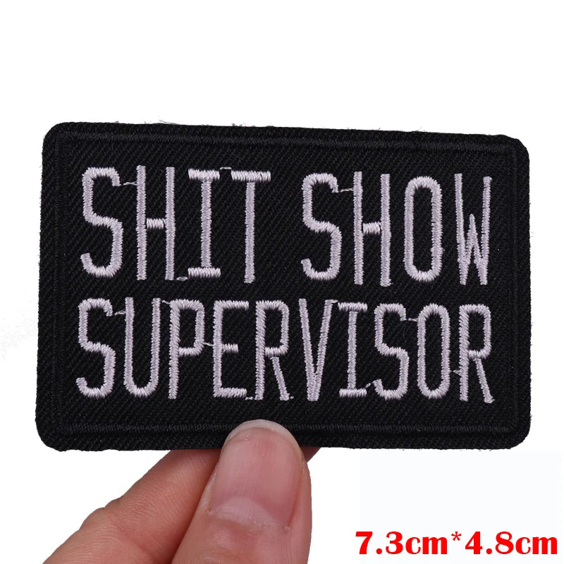 Embroidered patch with 'SHIT SHOW SUPERVISOR' text held by a hand, with dimensions displayed.