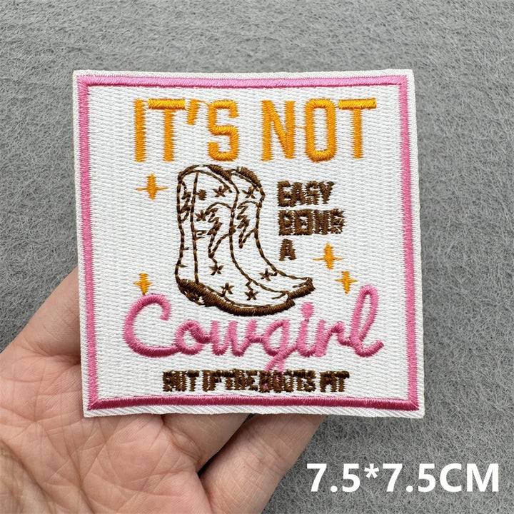 Embroidered patch with cowboy boot and text held in hand on a gray background