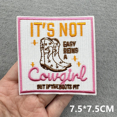 Embroidered patch with cowboy boot and text held in hand on a gray background
