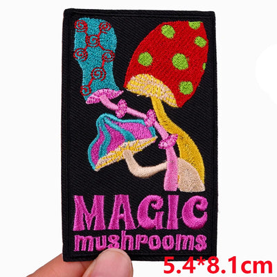 Embroidered patch with mushrooms and 'MAGIC mushrooms' text held by a hand.