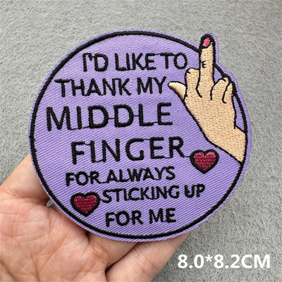 Patch with text 'I'd like to thank my middle finger for always sticking up for me' held by a hand on a gray background.