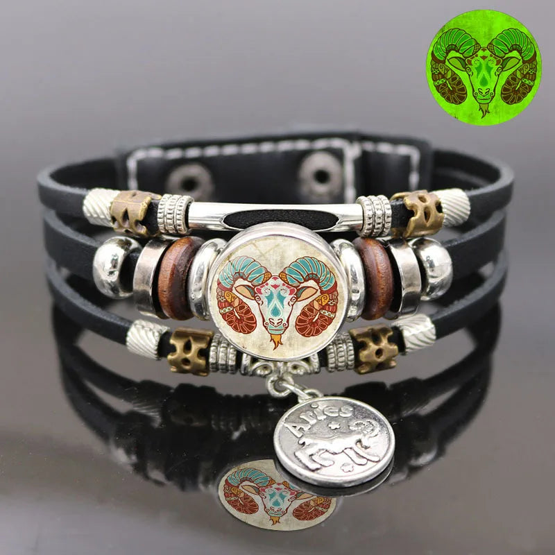 Black leather bracelet with silver, gold, and wooden beads featuring a zodiac symbol on a gray background.