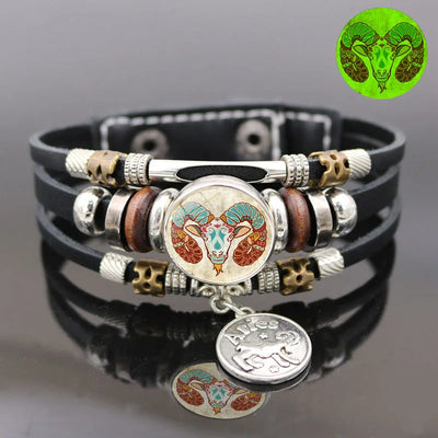 Black leather bracelet with silver, gold, and wooden beads featuring a zodiac symbol on a gray background.