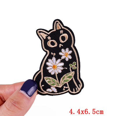 Black cat patch with flowers held by a hand on a white background