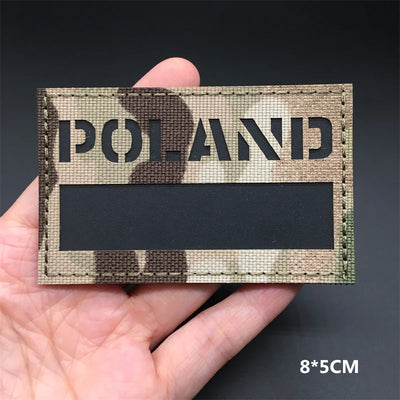 POLAND flag Camouflage patch held in a hand against a dark background