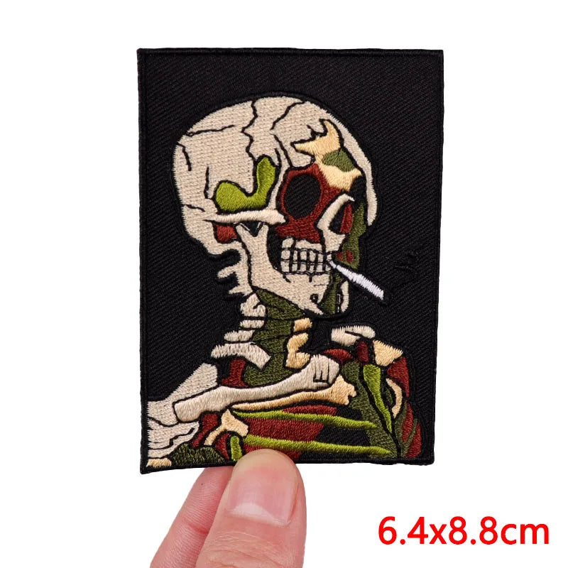 Embroidered patch of a skeleton smoking a cigarette with a hand holding it, on a black background.
