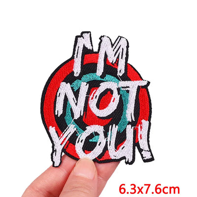 Embroidered patch with 'I'm Not You' text held by a hand on a white background
