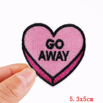 Heart-shaped patch with 'GO AWAY' text held by a hand on a white background