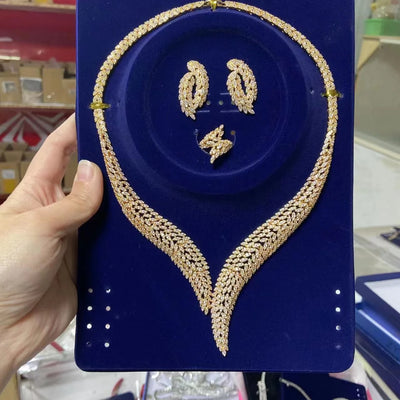 Gold necklace ring and earrings on a blue display card held by a hand.