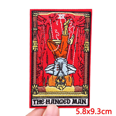 Tarot card patch of 'The Hanged Man' held by a hand with dimensions indicated.