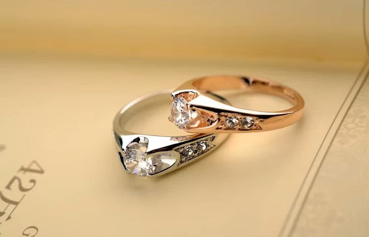 Pair of gold and silver rings with gemstones on a beige background