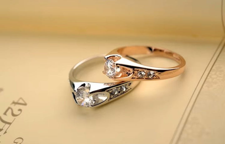 Pair of gold and silver rings with gemstones on a beige background