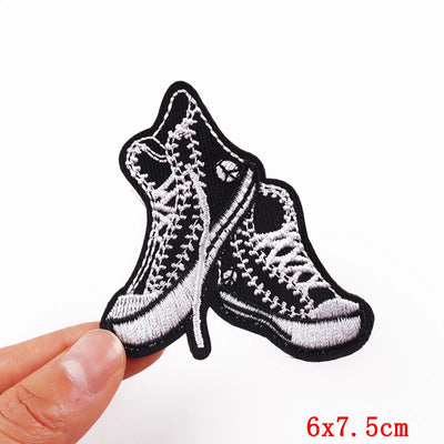 Embroidered patch of a shoe design held by a hand on a white background