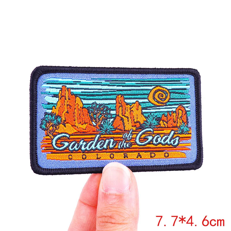 Embroidered patch of 'Garden of the Gods, Colorado' held by a finger on a white background.