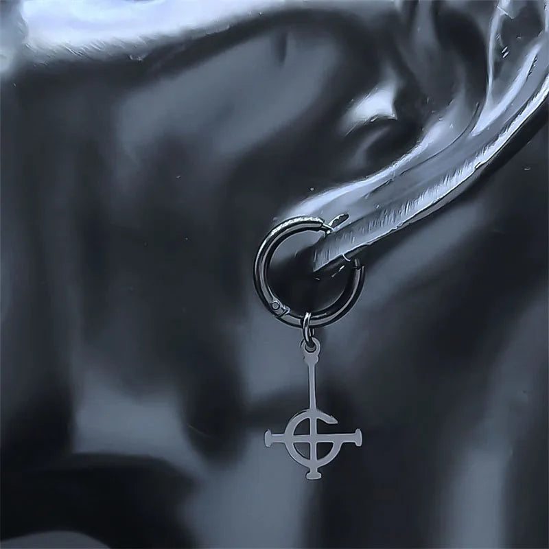 Close-up of an ear with a black earring featuring a silver pendant.