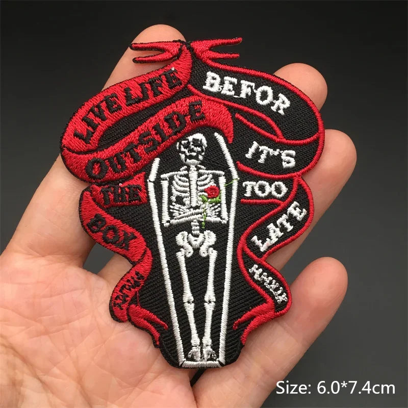 Embroidered patch with skeleton design and text held in a hand