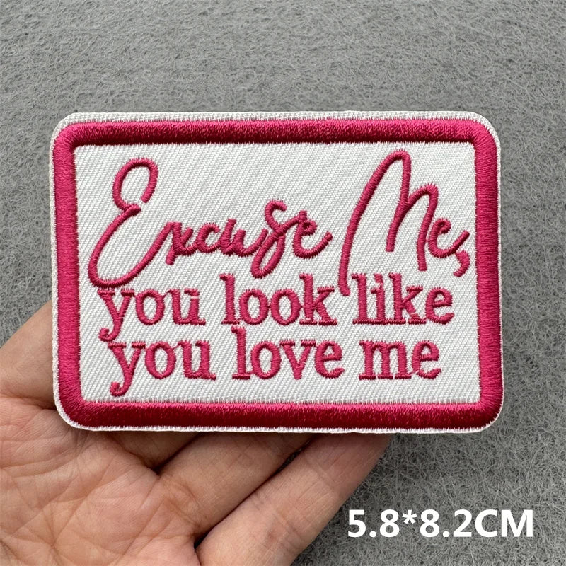 Embroidered patch with text held by a hand on a gray background