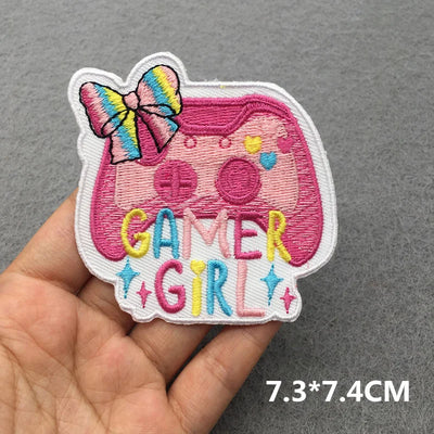 Embroidered patch with 'Gamer Girl' text and a bow held by a hand on a gray background.