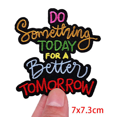 Motivational patch with colorful text held by a finger on a white background