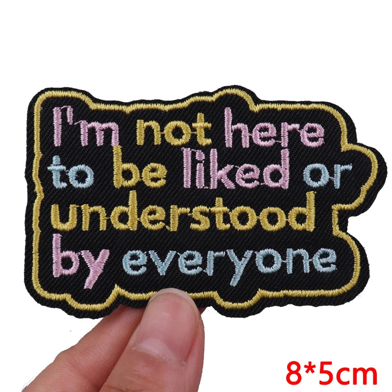 Embroidered patch with text 'I'm not here to be liked or understood by everyone' held by a hand.