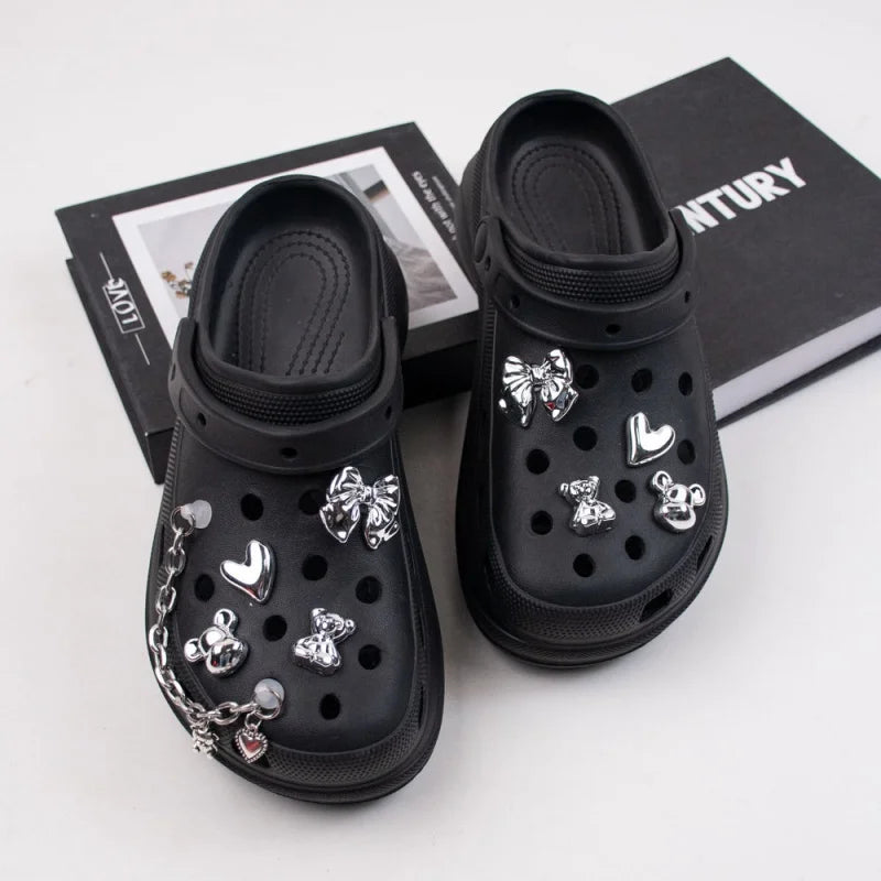 Black clogs with various charms on a white surface