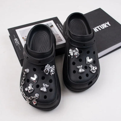 Black clogs with various charms on a white surface