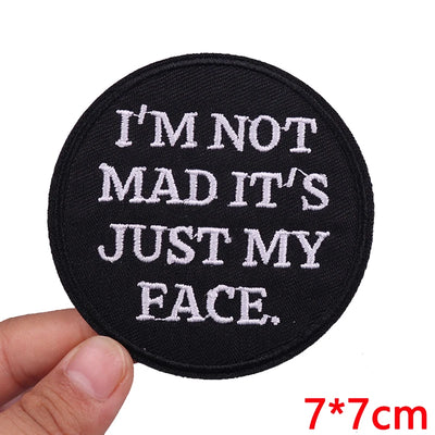 Black patch with white text 'I'M NOT MAD IT'S JUST MY FACE.' held by a hand, with size '7*7cm' displayed.