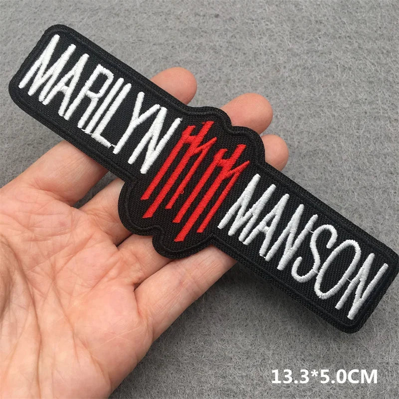 Hand holding a black red and white Marilyn Manson embroidered iron-on patch 13.3x5cm on a grey background