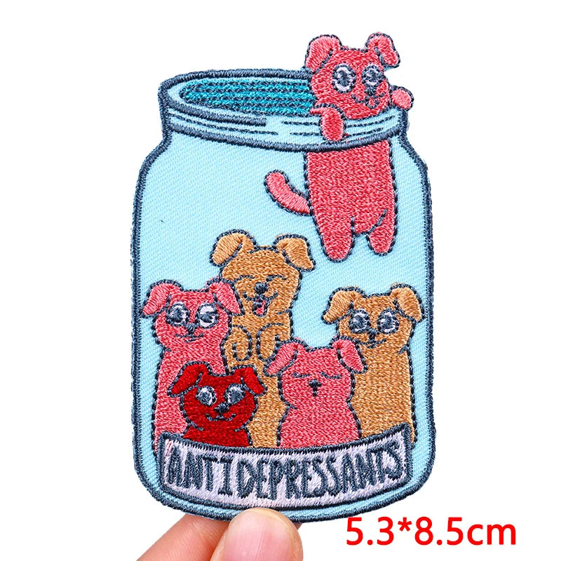 Embroidered patch with cartoon dogs in a jar labeled 'Antidepressants' held by a hand.