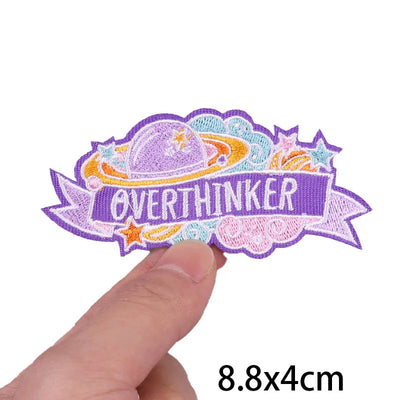 Embroidered patch with 'OVERTHINKER' text held by a hand on a white background